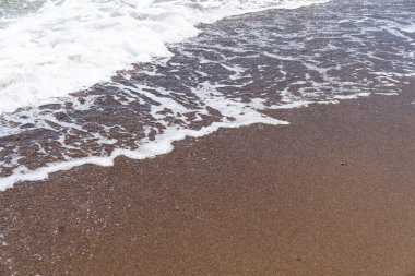 Güzel mavi deniz, büyük sakin dalgalar ve köpük. Denizde çakıl taşlarının üzerinden dalga geçiyor. Yuvarlanan okyanus dalgaları. Yaz cenneti sahili arka planı. Güçlü deniz dalgaları