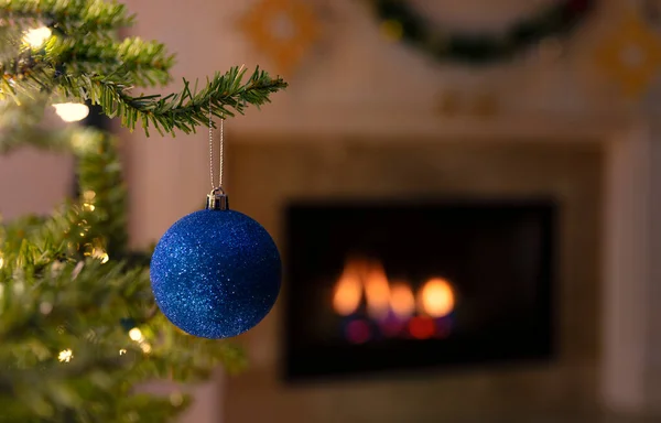 Zbliżenie Jeden Niebieski Świąteczny Ozdoba Wisząca Drzewie Świecącym Kominkiem Tle — Zdjęcie stockowe