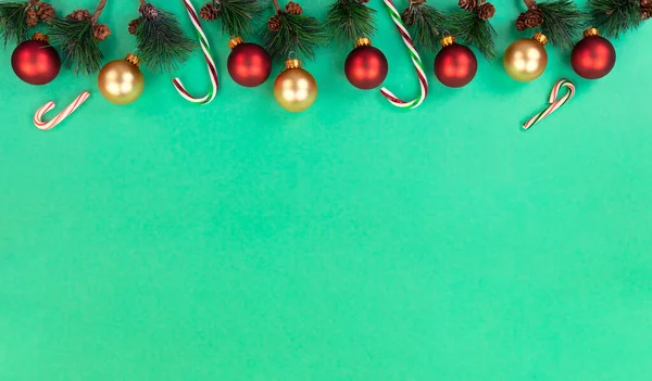メリークリスマスと幸せな新年の背景にモミの先端の枝 赤いボールの装飾品と緑のキャンディ缶 — ストック写真