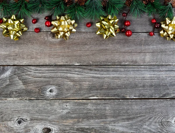 メリークリスマスまたは幸せな新年の背景にモミの先端の木の枝と素朴な木の板に金の弓 — ストック写真