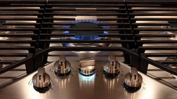 现代厨房炉顶用控制旋钮和金属烤架烹调 用金属烤炉在天然气炉炉灶上燃烧的气体火焰 图库照片