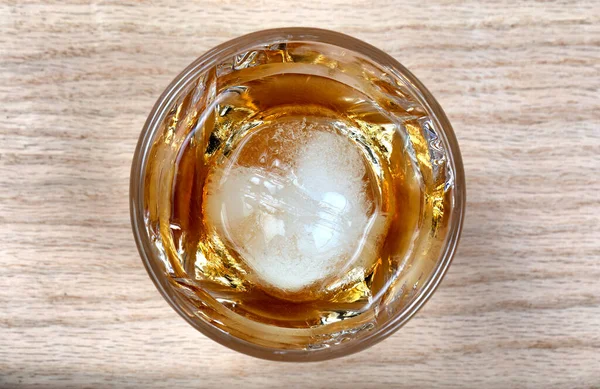 木製のテーブルの上に丸い氷のキューブとウィスキーを飲むのガラスの近くのビューをオーバーヘッド — ストック写真