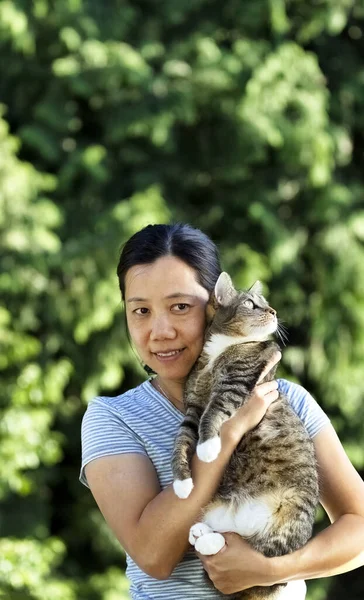 在一个阳光明媚 背负着树木的夏日 一个成熟的女人牵着她的宠物猫在户外 — 图库照片