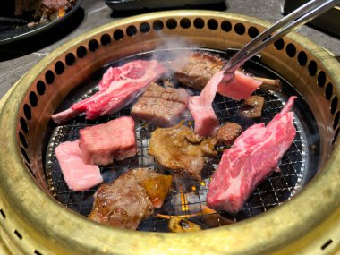 Japon BBQ tarzı bir ızgara ızgarasına çiğ et konmasına yakın çekim.  