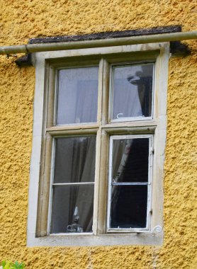 Cotswold 'daki Combe Köyü' nde eski bir kır evinin cephesinde sarmaşıkla çerçevelenmiş geleneksel bir pencerenin resmini kapat.