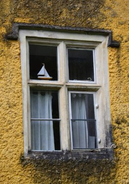 Cotswold 'daki Combe Köyü' nde eski bir kır evinin cephesinde sarmaşıkla çerçevelenmiş geleneksel bir pencerenin resmini kapat.