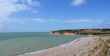 Seven Sisters Cliffs 'deki Cuckmere Haven manzarası denizi, sahili ve arka plandaki binaları gösteriyor. Seaford, Doğu Sussex, İngiltere İngiltere