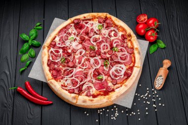 Jambonlu, sosisli, biberli ve soğanlı baharatlı pizza. Koyu arka planda İtalyan pizzası. Menü için pizza fotoğrafı