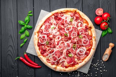 Jambonlu, sosisli, biberli ve soğanlı baharatlı pizza. Koyu arka planda İtalyan pizzası. Menü için pizza fotoğrafı