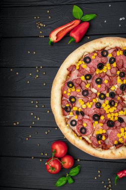 Lezzetli ve farklı et çeşitleriyle büyük pizza. Sosisli, jambonlu, mısırlı ve zeytinli pizza. Sıcak pizzanın en üst görüntüsü.