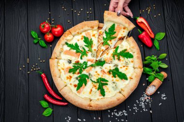 Somon, roka ve ahşap masada yenmeye hazır farklı baharatlarla nefis sıcak pizza. Lezzetli ve farklı et çeşitleriyle büyük pizza. Büyük pizzanın en üst görüntüsü