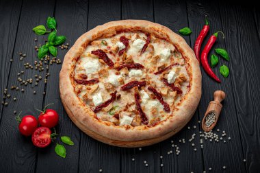 Lezzetli ve farklı et çeşitleriyle büyük pizza. Sıcak pizzanın en iyi manzarası. Kurutulmuş domatesli ve peynirli büyük ve lezzetli bir pizza.