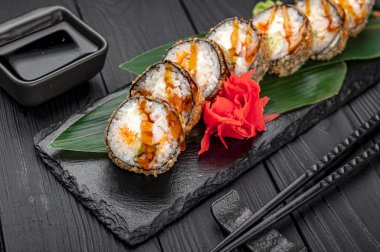 Somon ve peynirli sıcak tempura, siyah arka planda geleneksel lezzetli suşi rulosu. Suşi menüsü. Japon mutfağı, restoran. Asya yemekleri