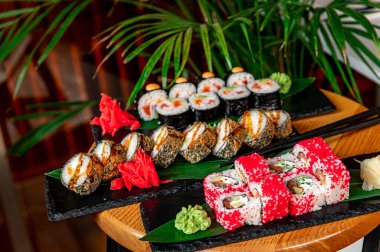 Büyük bir Asya yemeği takımı. Suşi ve siyah bir arka planda yuvarlanma. Sağlıklı yemek.