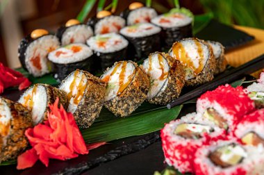 Büyük bir Asya yemeği takımı. Suşi ve siyah bir arka planda yuvarlanma. Sağlıklı yemek.