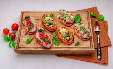 Geleneksel İtalyan antipasto bruschetta aperatifi et, balık, yeşillik ve balzamik sirkeyle birlikte. Sığır eti, soğan, tatlı patates, somon, limon ve mikroyeşillik. Menü için fotoğraf.