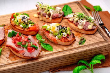Geleneksel İtalyan antipasto bruschetta aperatifi et, balık, yeşillik ve balzamik sirkeyle birlikte. Sığır eti, soğan, tatlı patates, somon, limon ve mikroyeşillik. Menü için fotoğraf.