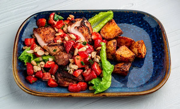 Duck breast with strawberries, tomatoes, nuts and baked potatoes. Healthy and delicious food. Photo for the menu.