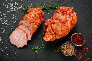 Smoked meat on a wooden table with addition of fresh herbs and aromatic spices. Natural product from organic farm, produced by traditional methods