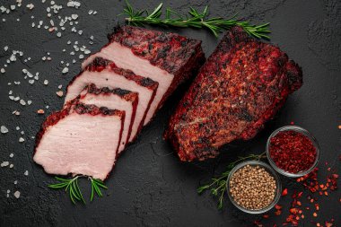 Smoked meat on a wooden table with addition of fresh herbs and aromatic spices. Natural product from organic farm, produced by traditional methods