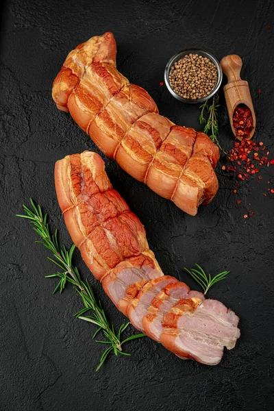 Smoked meat on a wooden table with addition of fresh herbs and aromatic spices. Natural product from organic farm, produced by traditional methods