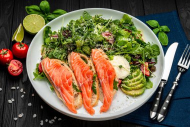 Taze salata ve ahşap arka planda krem peynirli kızarmış somon balığı. Sağlıklı gıda konsepti.