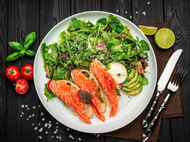 Taze salata ve ahşap zemin üzerinde parmesan peynirli kızarmış somon balığı. Sağlıklı gıda konsepti.