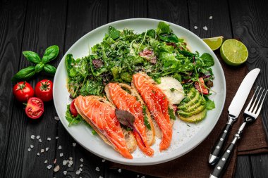 Taze salata ve ahşap zemin üzerinde parmesan peynirli kızarmış somon balığı. Sağlıklı gıda konsepti.