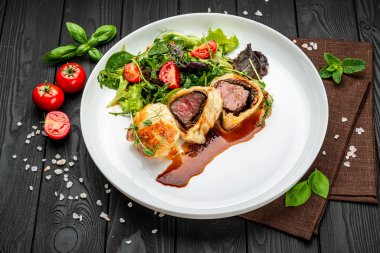 Wellington usulü sığır eti, klasik biftek, yeşil salatalı klasik tarif. Restoranda yemek servisi. Sağlıklı gıda konsepti. Menü için fotoğraf