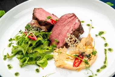 Salata ve humus ile dana madalyonu. Restoranda yemek servisi. Sağlıklı gıda konsepti. Menü için fotoğraf