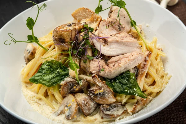 Plate of chicken pasta on a rustic wooden table. Serving food in a restaurant. Healthy food concept. Photo for the menu