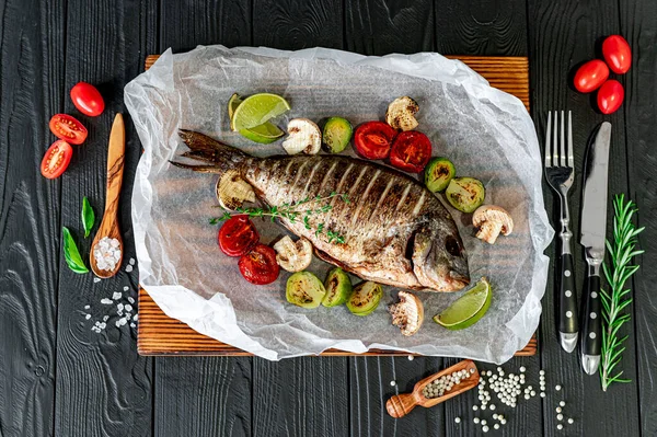 Grilled Dorada fish, sea bream with the addition of spices, herbs and lemon on the grill plate. Fried fish with vegetables
