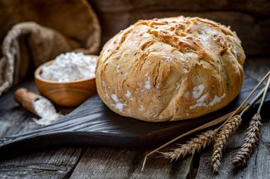 Tahta bir masada taze ev yapımı ekmek. Sağlıklı yiyecekler. Eski bir tarife göre fırında ekmek pişirmek..
