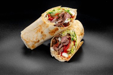 Beef shawarma on a dark background. Shawarma with beef in pita bread. Photo for the menu