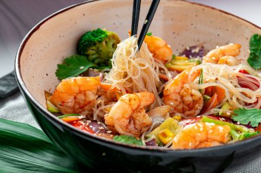 Rice noodles with shrimp and vegetables. Asian cuisine. Delicious and healthy food. Photo for the menu.