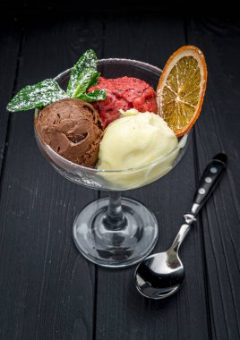 Koyu arkaplandaki cam bardaktaki farklı dondurma türleri. Menü için fotoğraf