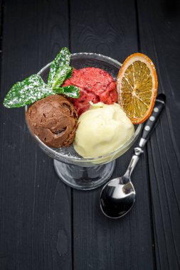 Koyu arkaplandaki cam bardaktaki farklı dondurma türleri. Menü için fotoğraf