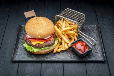 Siyah ahşap bir masada lezzetli hamburger ve patates kızartması. Menü için fotoğraf