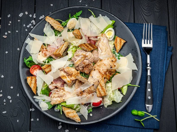 stock image Fresh caesar salad in white plate on dark wooden table. Top view. Photo for the menu