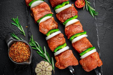 raw kebab with vegetables. On a black stone background