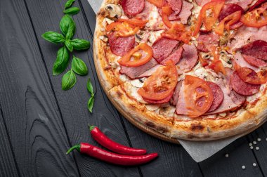 Jambonlu İtalyan pizzası, sosis, mantar, domates ve soğanlı. Koyu arka planda İtalyan pizzası. Menü için pizza fotoğrafı