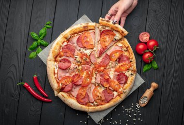 Jambonlu İtalyan pizzası, sosis, mantar, domates ve soğanlı. Koyu arka planda İtalyan pizzası. Menü için pizza fotoğrafı