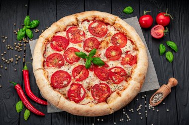 Siyah arka planda pizza margherita, üst manzara. Domates, fesleğen ve Mozzarella peynirli pizza..