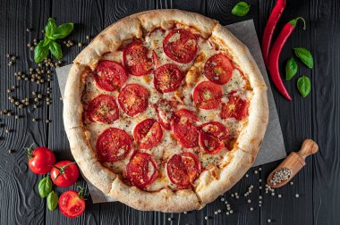 Siyah arka planda pizza margherita, üst manzara. Domates, fesleğen ve Mozzarella peynirli pizza..