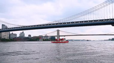 Kırmızı tekne Manhattan Köprüsü 'ne ve Brooklyn Köprüsü' ne gidiyor. New York, ABD 'deki East River' da seyrüsefer.