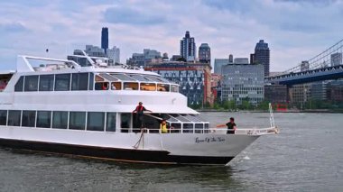 New York, ABD, 4 Temmuz 2025: Nehir teknesinde can yeleği giyen çok az kişi duruyor. Su aracı New York 'ta East River' dan geçiyor. Arkaplanda ünlü Manhattan Köprüsü.