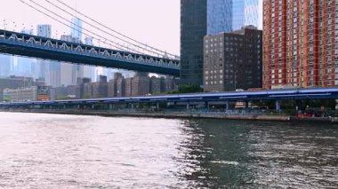 New York, ABD, 4 Temmuz 2025: Doğu Nehri 'nin kıyısı boyunca seyahat edin. Manhattan Köprüsü 'nün alçak açılı görüntüsü. New York gökyüzü sisli arka planda.