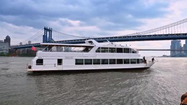 New York, ABD, 4 Temmuz 2025: Doğu Nehri 'nin arkasında Amerikan bayrağı olan modern nehir teknesi. Su aracı Manhattan Köprüsü 'ne doğru gidiyor. New York, ABD.