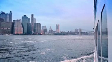 New York, ABD 'de East River' da Riverboat turu. Kasvetli bir günde Brooklyn Köprüsü 'ne kıyıdan yaklaşıyoruz. Arkaplanda Manhattan 'ın silüeti.