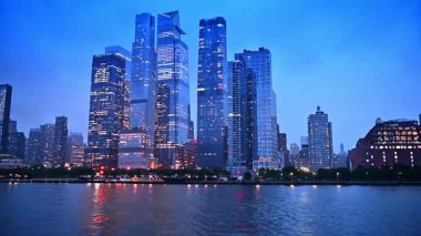 New York 'un güzel, modern gökdelenleri ve pencereleri açık. Alacakaranlıkta su manzarasından binaların alçak açılı görüntüsü.